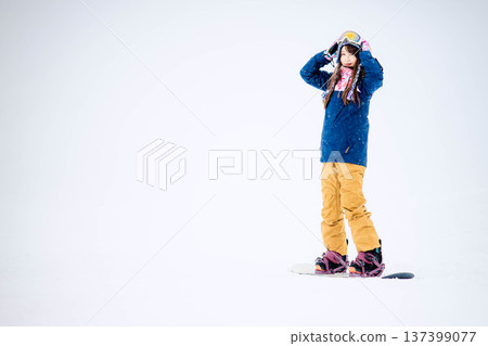年輕女子在滑雪勝地的山坡上享受冬季運動-單板滑雪。 年輕女子在滑雪勝地的山坡上享受冬季運動-單板滑雪。 137399077