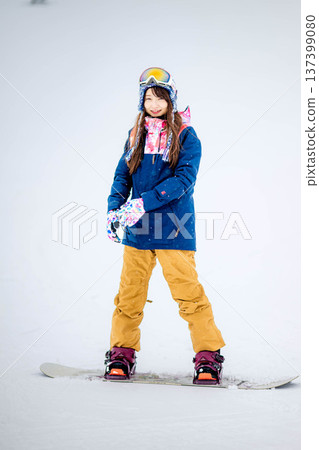 Young woman enjoying winter sports snowboarding on the slopes of a ski resort 137399080