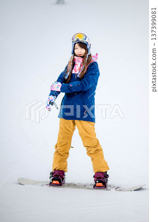 年輕女子在滑雪勝地的山坡上享受冬季運動－單板滑雪。 137399081