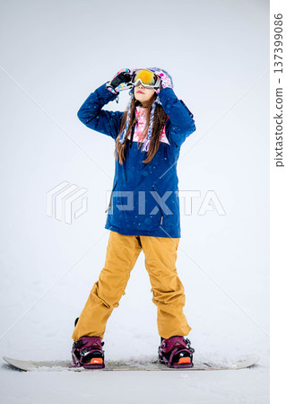 年輕女子在滑雪勝地的山坡上享受冬季運動－單板滑雪。 137399086