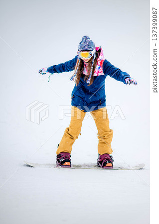 年輕女子在滑雪勝地的山坡上享受冬季運動-單板滑雪。 年輕女子在滑雪勝地的山坡上享受冬季運動-單板滑雪。 137399087