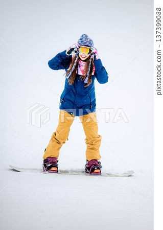 年輕女子在滑雪勝地的山坡上享受冬季運動－單板滑雪。 137399088