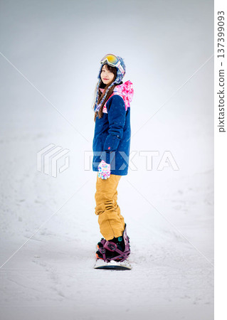 年輕女子在滑雪勝地的山坡上享受冬季運動－單板滑雪。 137399093