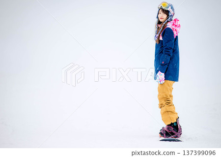 Young woman enjoying winter sports snowboarding on the slopes of a ski resort Young woman enjoying winter sports snowboarding on the slopes of a ski resort 137399096