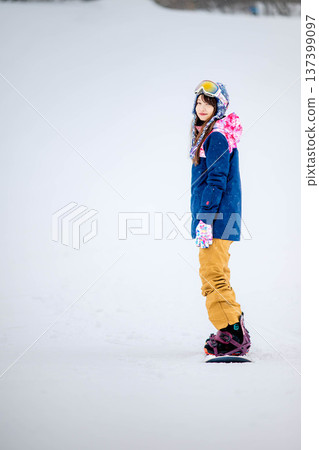 Young woman enjoying winter sports snowboarding on the slopes of a ski resort Young woman enjoying winter sports snowboarding on the slopes of a ski resort 137399097