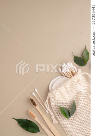 Reusable cotton pads, a bamboo toothbrush, and bamboo cotton swabs in a mesh bag promote eco-friendliness and conscious consumption. Green lifestyle, environmental awareness 137399443