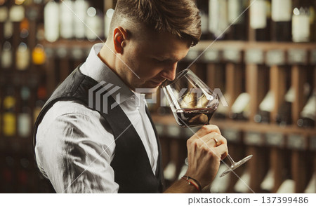 Close-up shot of young sommelier smell red wine on wine cellar background. 137399486