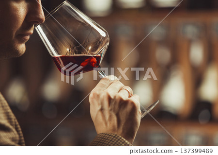 Close-up shot of professional sommelier smell red wine on wine cellar background. Close-up shot of professional sommelier smell red wine on wine cellar background. 137399489