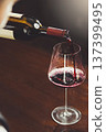 Close-up vertical image of bartender pours red wine to wineglass on bar counter background. 137399495