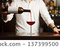Male sommelier pouring red wine into long-stemmed wineglasses. 137399500