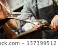 Sommelier pouring wine into glass from mixing bowl. Male waiter 137399512