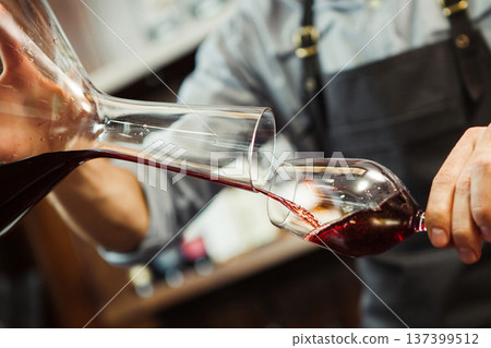 Sommelier pouring wine into glass from mixing bowl. Male waiter 137399512