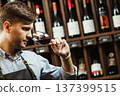 Bokal of red wine on background, male sommelier appreciating drink 137399515