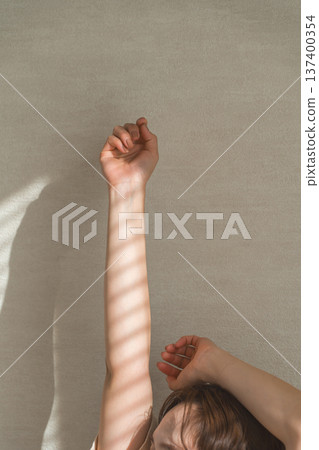 Hands of a woman stretching while bathing in the morning sun Hands of a woman stretching while bathing in the morning sun 137400354