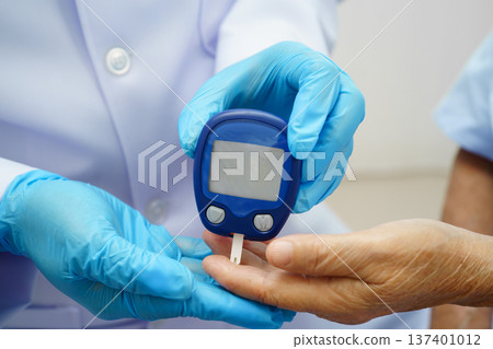 Asian doctor using digital glucose meter for check sample blood sugar level to treatment diabetes. 137401012