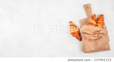 Fresh Croissants in Paper Bag on Wooden Board Top View 137401133