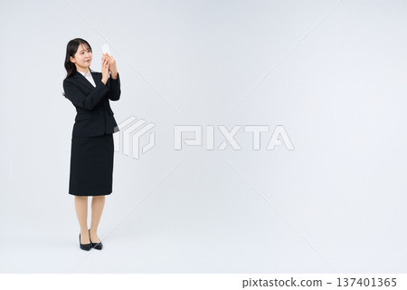 Businesswoman holding up a smartphone Businesswoman holding up a smartphone 137401365