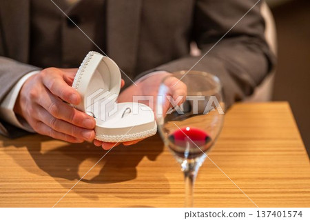 A man in a suit and tuxedo opening a jewelry case and ring case to show off a ring (marriage proposal) A man in a suit and tuxedo opening a jewelry case and ring case to show off a ring (marriage proposal) 137401574