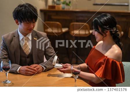 一名男子在餐廳向女子求婚，女子收到一枚戒指。 137401576