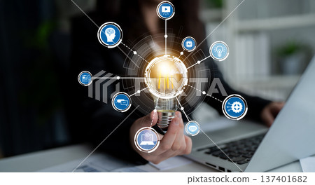 Creative Businesswoman Holding Light Bulb with Technology Icons Representing Innovation, Ideas, and Modern Solutions in a Professional Office Setting Crux 137401682