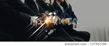 Business professionals in suits sitting in a row, with a rocket graphic symbolizing growth, innovation, and success for corporate strategies and projects. Trope Business professionals in suits sitting in a row, with a rocket graphic symbolizing growth, innovation, and success for corporate strategies and projects. Trope 137402296