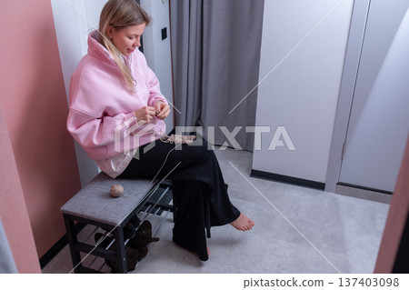 Young woman knitting at home in casual indoor setting Young woman knitting at home in casual indoor setting 137403098