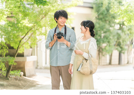 Man and woman taking photos with a single-lens reflex camera on a trip 137403103