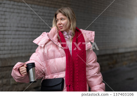 Young blonde woman walking with coffee on winter city street 137403106