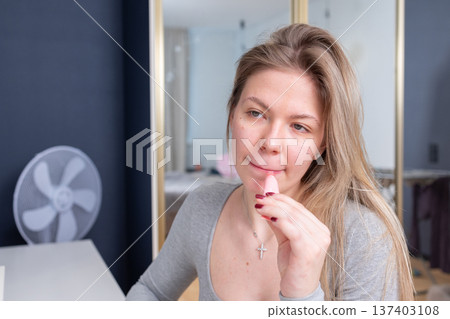 Young woman applying lipstick at home mirror beauty routine Young woman applying lipstick at home mirror beauty routine 137403108