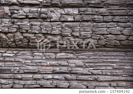 Burnt wood surface creating a detailed texture, showing damage and charcoal patterns from fire Burnt wood surface creating a detailed texture, showing damage and charcoal patterns from fire 137404192