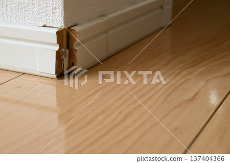 Damaged and peeling baseboards along the walls of a house 137404366