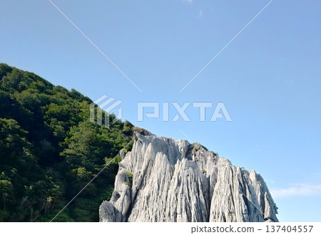The white rock formations and green mountains of Hotokegaura towering under the blue sky 137404557
