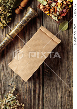 Brown paper bag and bundles of dried medicinal herbs on an old wooden table. 137405167