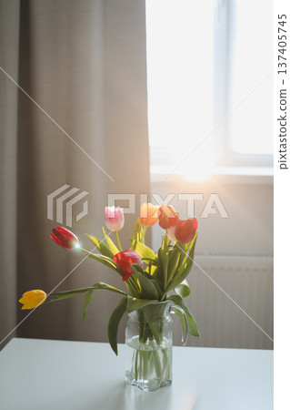 Fresh spring colorful bouquet of tulips in vase standing on white table in light classic design living room background. Festive flowers for gift. Mockup for greeting card 137405745