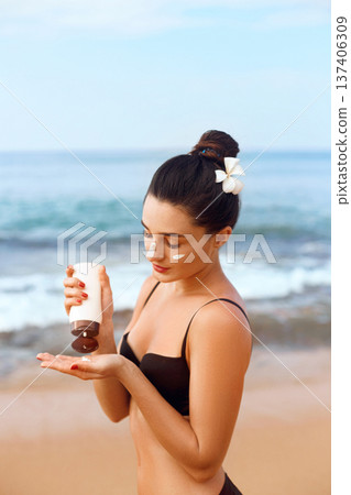 Suntan Lotion. Sexy Young Woman Applying Sunscreen Solar Cream on the beach.Sun Protection. Sun Cream. Skin and Body Care.Girl Holding Moisturizing Sunblock. Skin Protection Suntan Lotion. Sexy Young Woman Applying Sunscreen Solar Cream on the beach.Sun Protection. Sun Cream. Skin and Body Care.Girl Holding Moisturizing Sunblock. Skin Protection 137406309