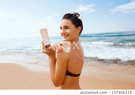 Woman putting sunblock lotion on shoulder before tanning during summer holiday on beach vacation resort Woman putting sunblock lotion on shoulder before tanning during summer holiday on beach vacation resort 137406318
