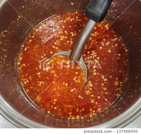 Homemade Spicy Sweet Red Chili Sauce with Seeds Stirred in a Metal Pot Homemade Spicy Sweet Red Chili Sauce with Seeds Stirred in a Metal Pot 137406950