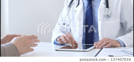 Doctor man showing information on tablet to patient woman during medical visit, explaining diagnosis and treatment options, providing medical consultation using modern technology. Medicine concept 137407039
