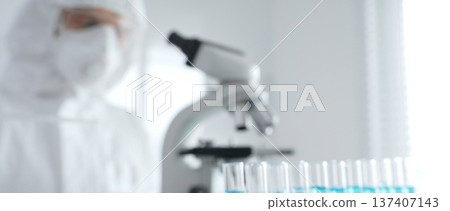 Scientific researcher wearing protective gear, carefully pipetting liquid into test tubes while conducting medical research experiment in laboratory. Medicine, healthcare and science concept Scientific researcher wearing protective gear, carefully pipetting liquid into test tubes while conducting medical research experiment in laboratory. Medicine, healthcare and science concept 137407143