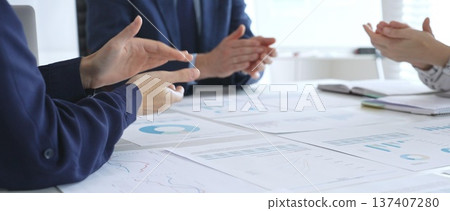 Teamwork and business collaboration with colleagues joining hands over financial charts, symbolizing unity, partnership, success, and strategic corporate planning 137407280