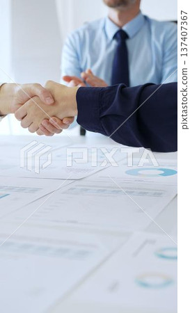 Business woman partners are shaking hands in office with financial charts, laptop and reports on table, symbolizing success, teamwork and agreement. Handshake concept Business woman partners are shaking hands in office with financial charts, laptop and reports on table, symbolizing success, teamwork and agreement. Handshake concept 137407367