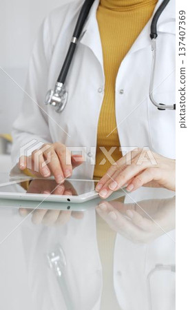 Doctor using tablet computer for digital health data, patient records, and medical application in clinic. Medicine, healthcare and science concept Doctor using tablet computer for digital health data, patient records, and medical application in clinic. Medicine, healthcare and science concept 137407369