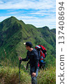 Male hiker with backpack and trekking poles looking at mountain 137408694
