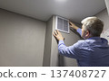 A person installing or maintaining an HVAC return air vent grille 137408727