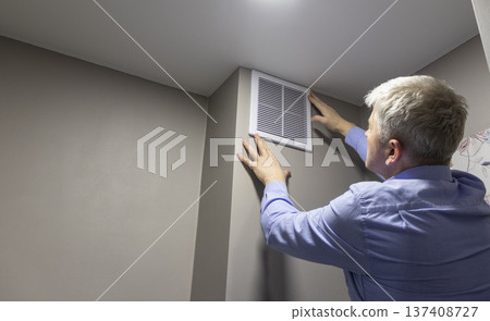 A person installing or maintaining an HVAC return air vent grille A person installing or maintaining an HVAC return air vent grille 137408727
