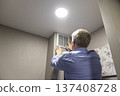 A person installing or maintaining an HVAC return air vent grille 137408728