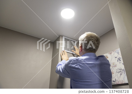 A person installing or maintaining an HVAC return air vent grille A person installing or maintaining an HVAC return air vent grille 137408728