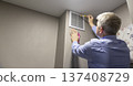 A person installing or maintaining an HVAC return air vent grille 137408729