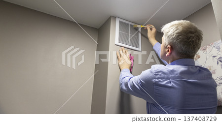 A person installing or maintaining an HVAC return air vent grille A person installing or maintaining an HVAC return air vent grille 137408729