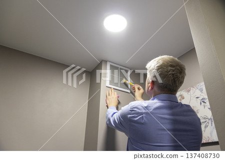 A person installing or maintaining an HVAC return air vent grille A person installing or maintaining an HVAC return air vent grille 137408730